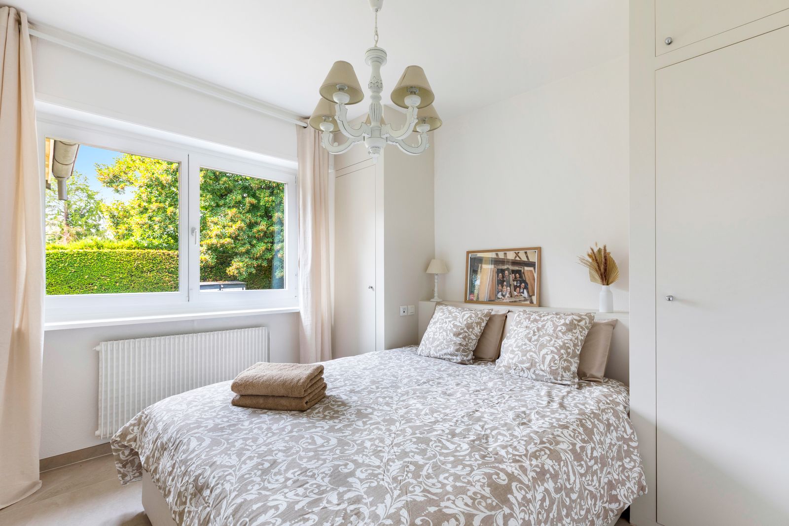 Chambre au lustre en verre et linge de lit à motifs feuillage