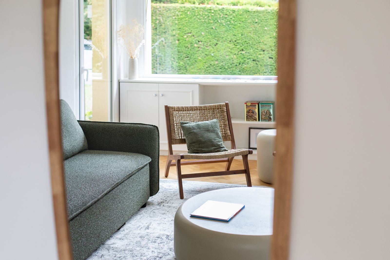 Fauteuil en rotin devant la baie ouverte sur la haie du jardin