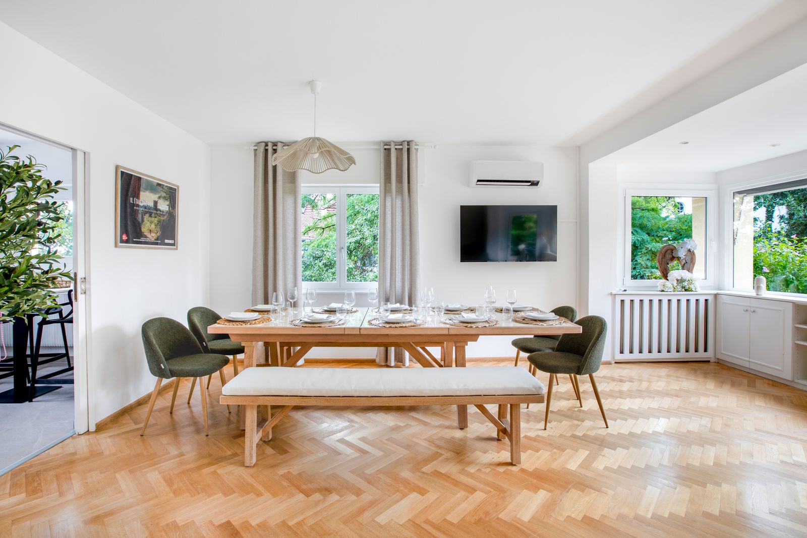 Salle à manger avec table en bois clair, banc et chaises vertes